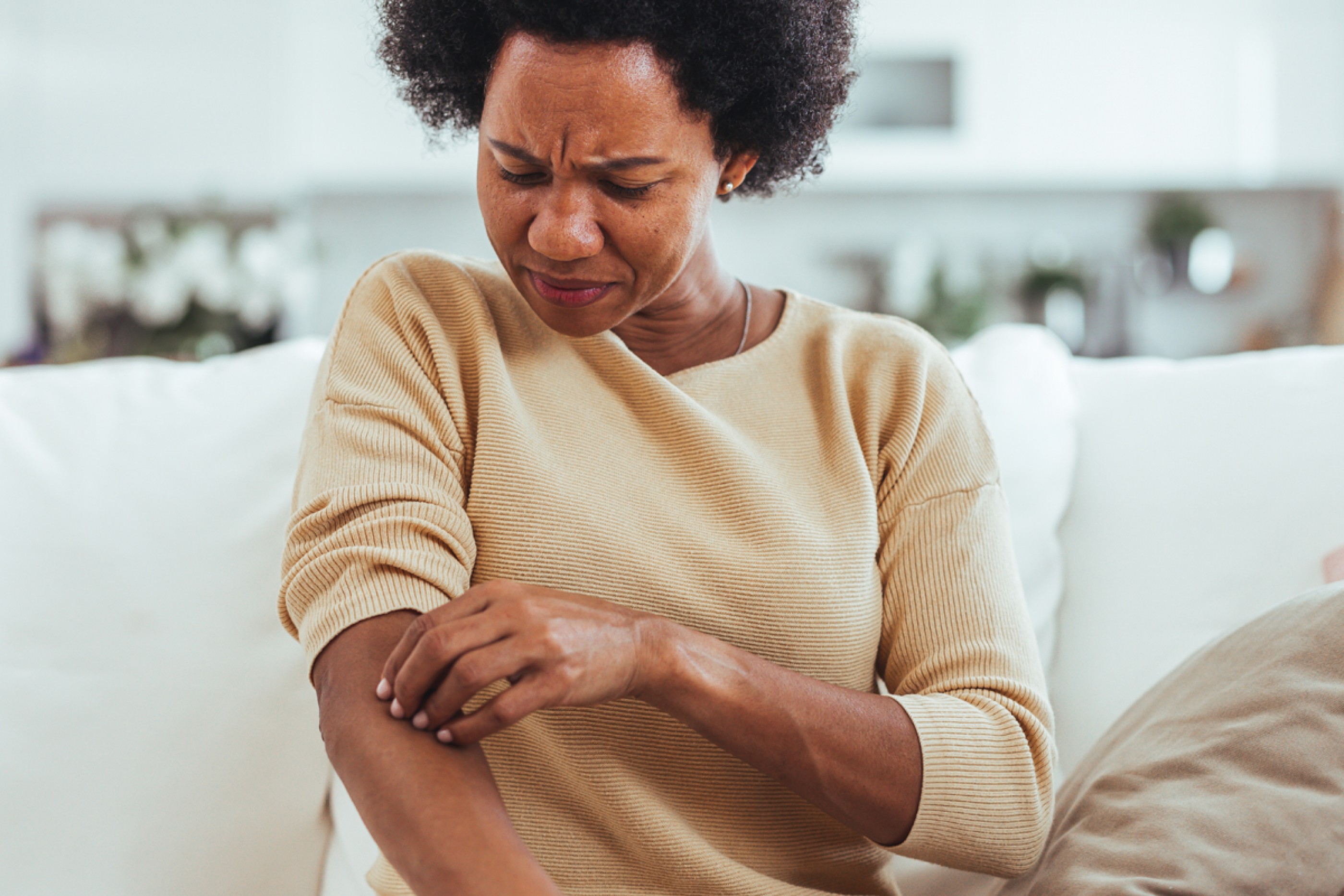 Dermatology care for skin of color—woman checking dark spots on the skin of her arm.